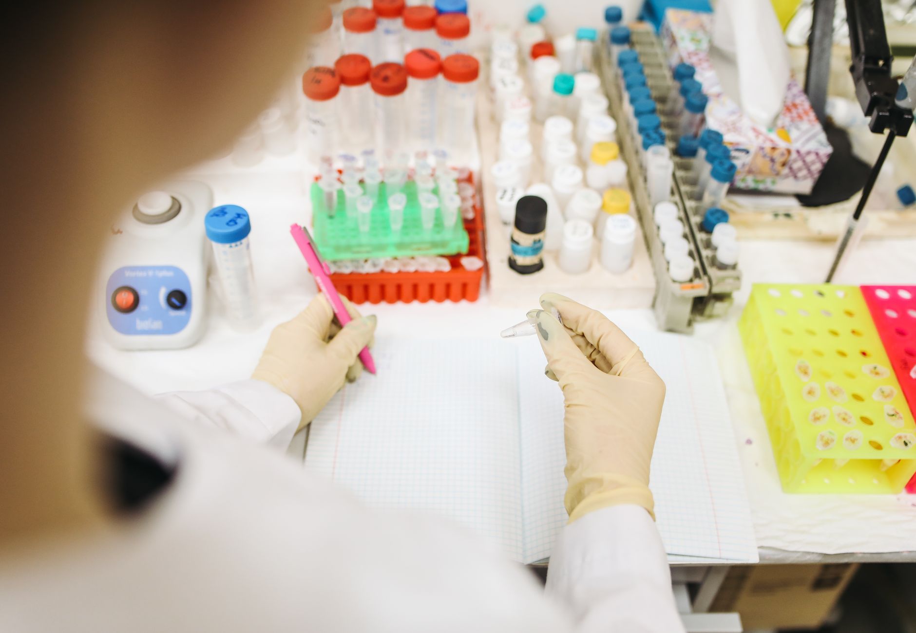 Scientist analyzing samples in a lab with various test tubes and equipment.