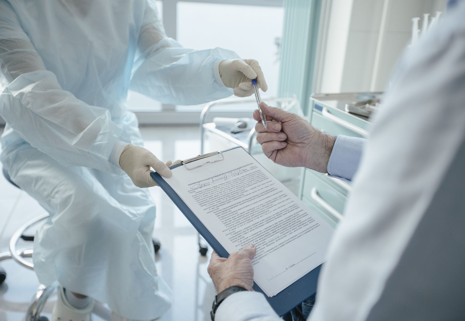 A doctor hands a clipboard to a patient for signature, highlighting medical professionalism.