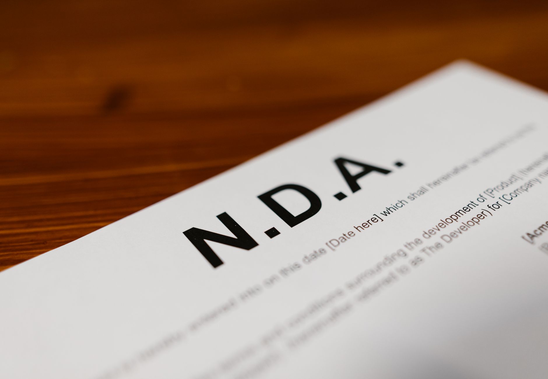 Focused close-up of an NDA document on a wooden desk, highlighting contract details.