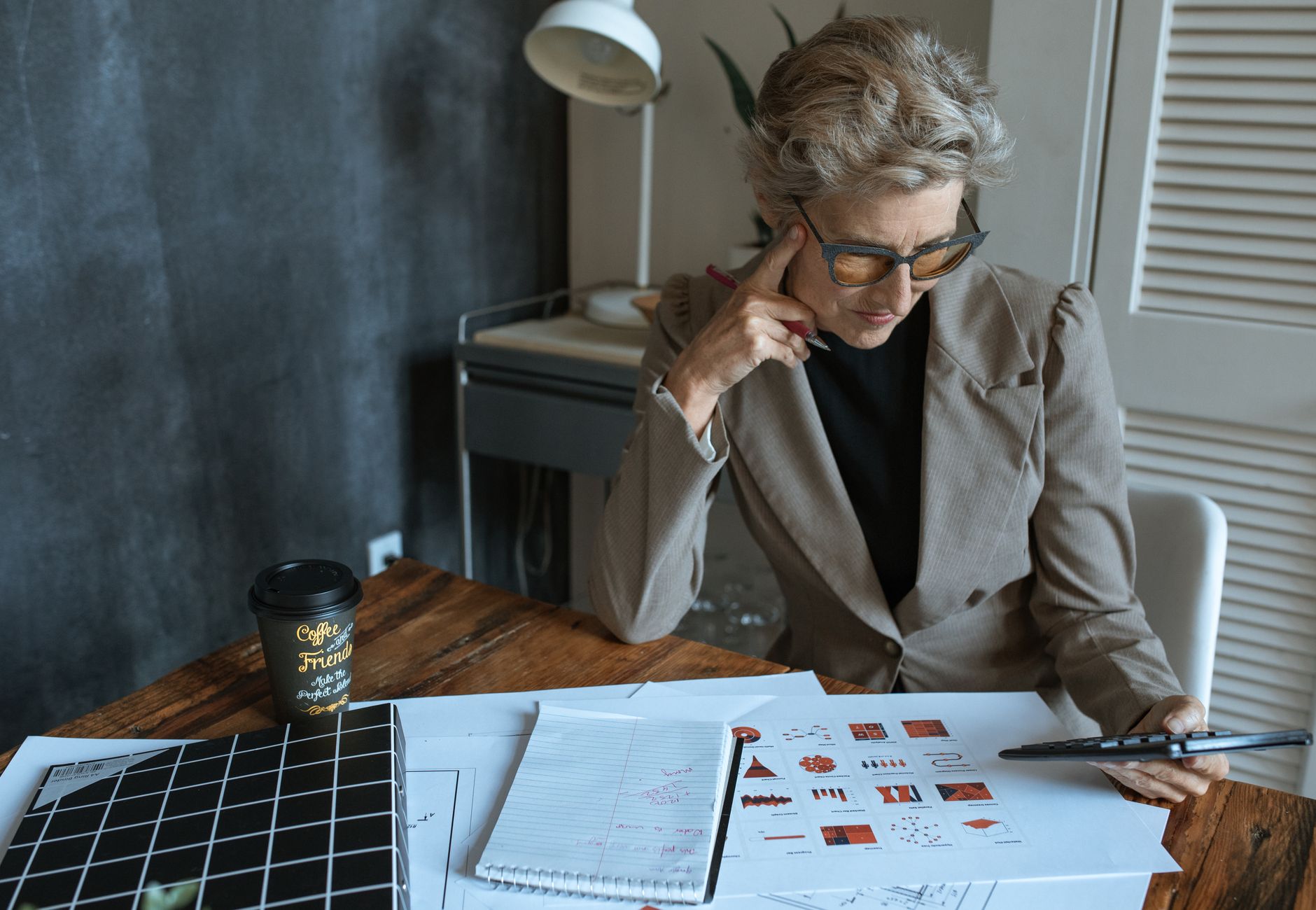 Focused businesswoman reviewing documents at desk in modern home office setting.