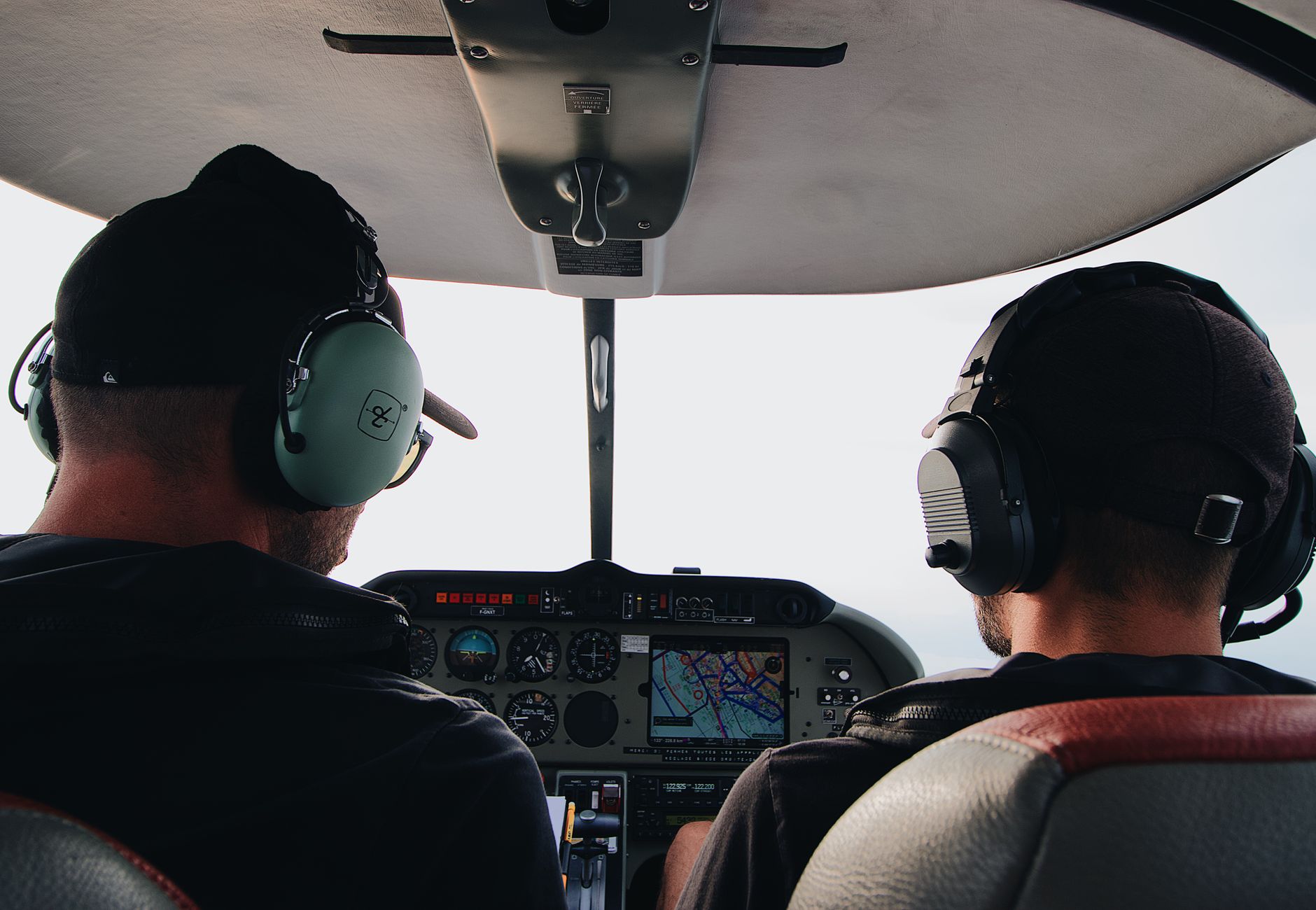 Two pilots with headsets operating controls in an aircraft cockpit.