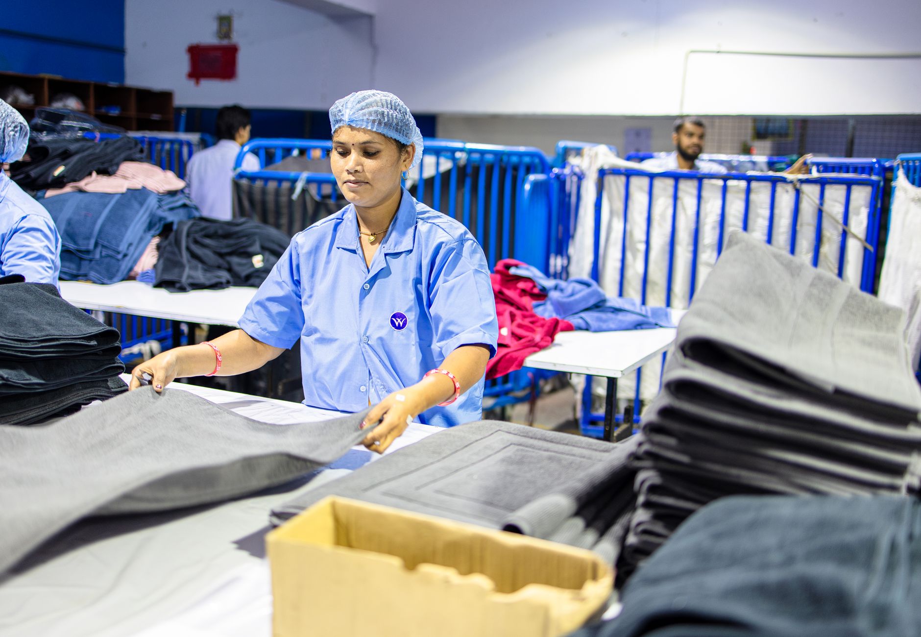 Workers folding fabric in a textile factory, highlighting industrial labor.