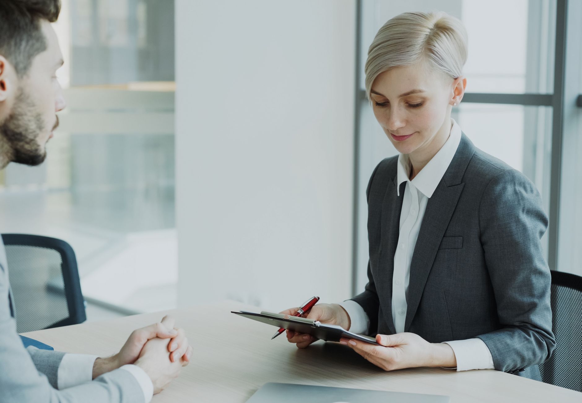 Two professionals in a modern office discussing business. Bright, professional setting.
